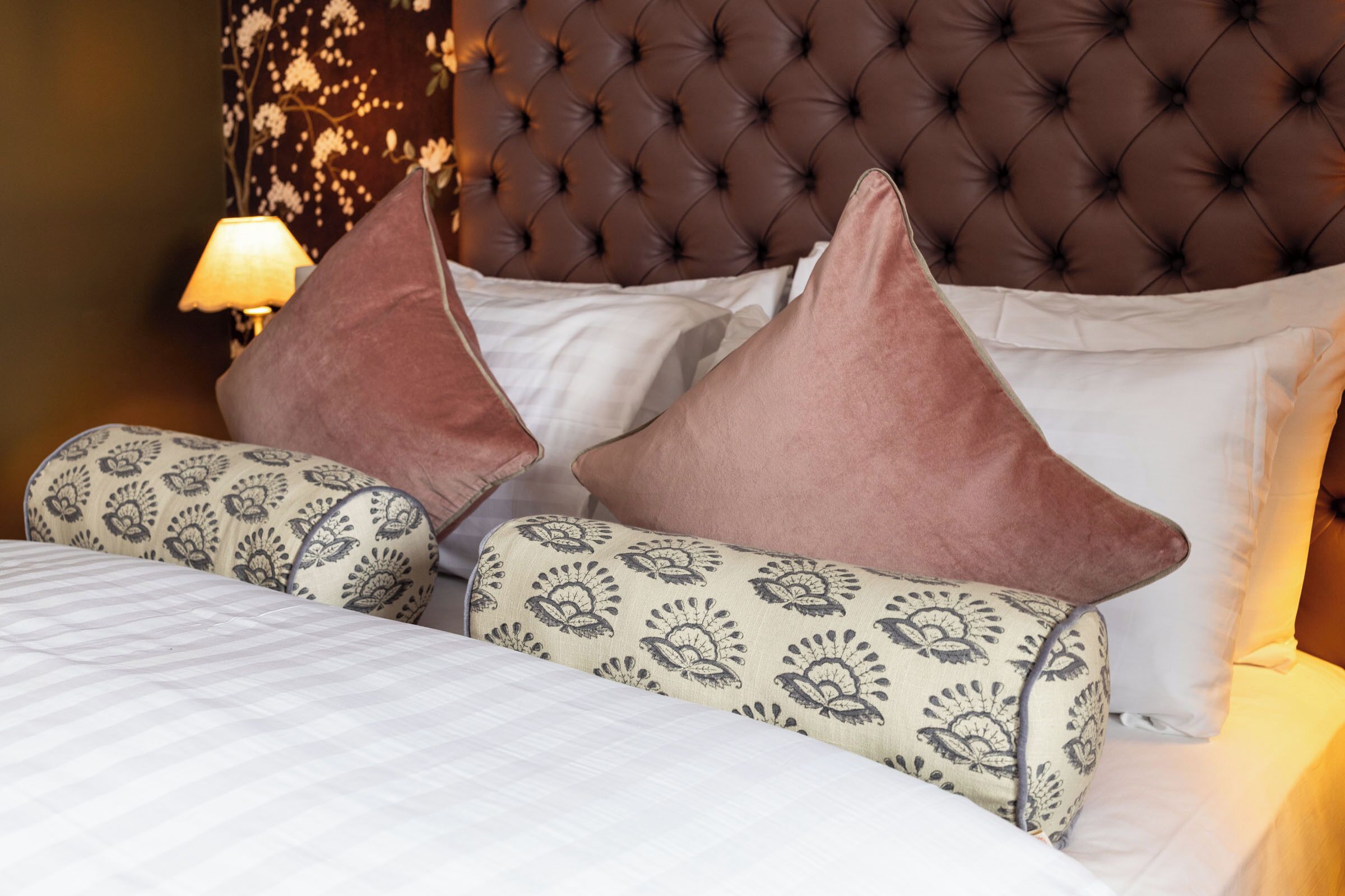 A neatly made bed with patterned pillows and a tufted headboard.