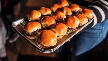 A tray of burgers with buns being held by a person.