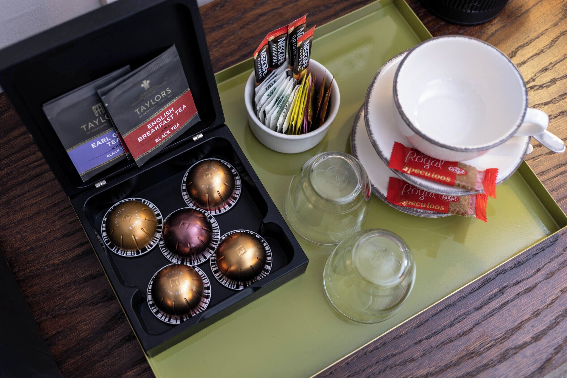 A tray with tea packets, a cup, and glasses.