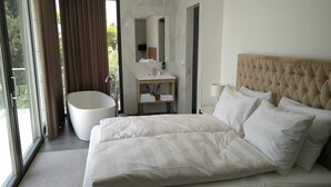 Een hotelkamer met een groot bed, een badkuip, een wastafel en een spiegel.