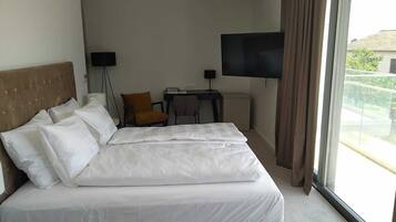 Habitación de hotel con una cama grande, un escritorio, una silla, un televisor y una ventana con vistas al exterior.