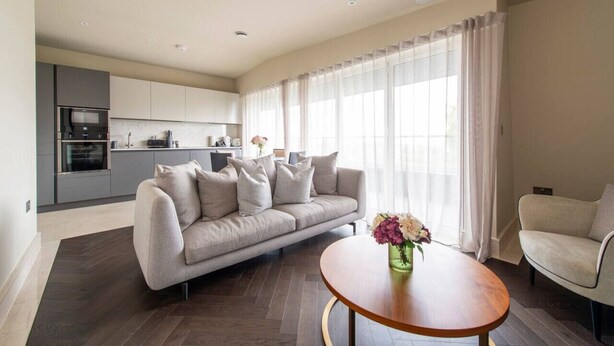 Ein modernes Wohnzimmer mit einer Couch, einem Couchtisch und einer Küche im Hintergrund.