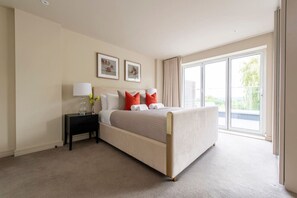 Relax in a serene space with a large bed, bedside table, and a beautiful view of lush greenery.