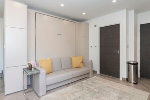 Relax in this inviting living area with a sofa, side table, and vase of flowers.