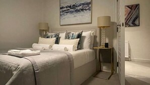 Een slaapkamer met een bed, twee nachtkastjes en een bijzetmeubel.
