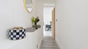 A hallway with a checkered container, a vase with flowers, and a mirror on the wall. - Beautiful Notting Hill Apt (Greater London)