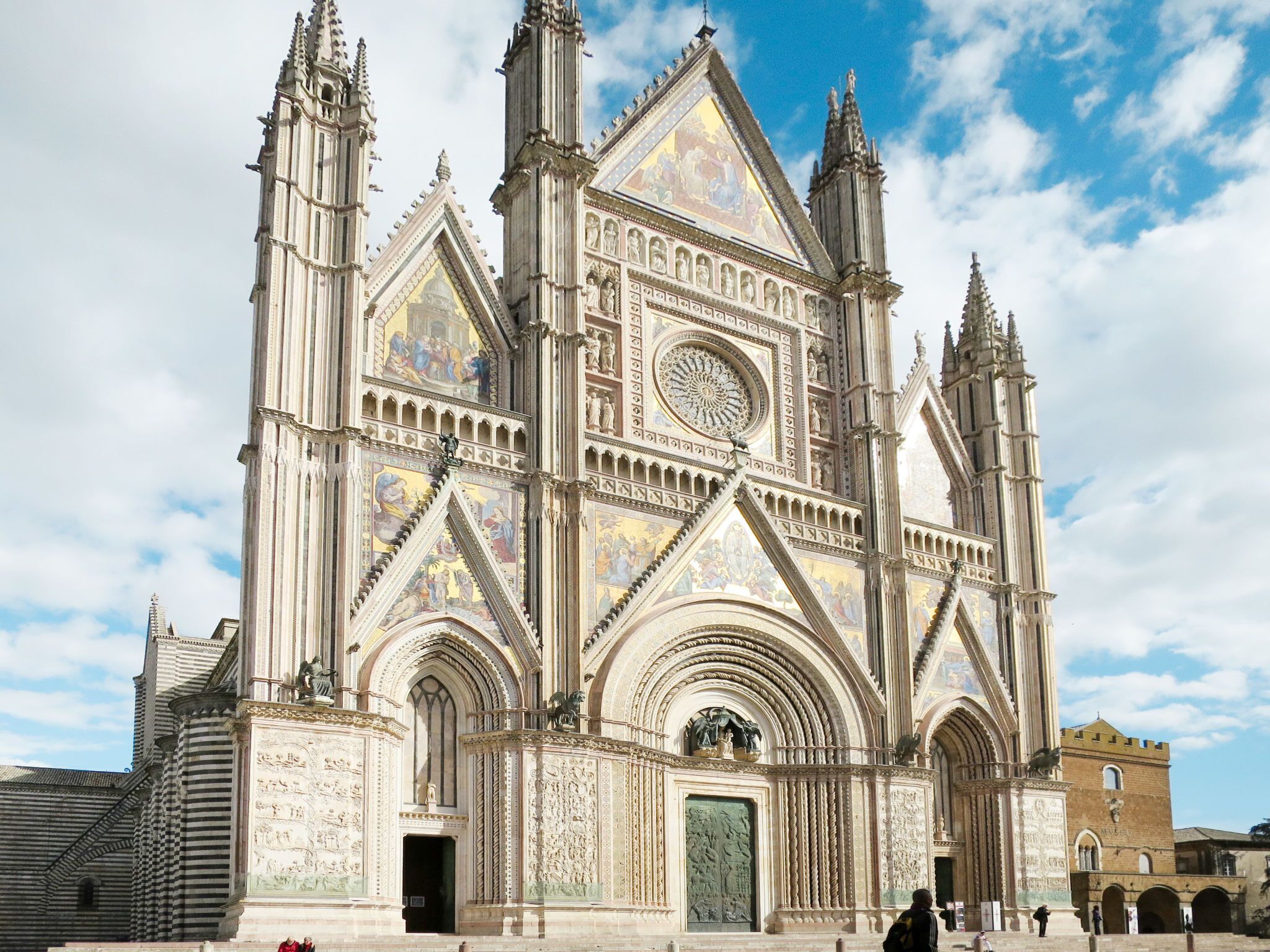 A large cathedral with intricate Gothic architecture, featuring pointed arches, detailed stone carvings, and a prominent rose window.