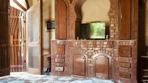 A room with a stone fireplace, a television, and a tiled floor. - Harmony Villas Sleeps 4 With Garden (Luxor)