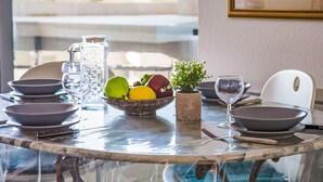 A dining table set with plates, bowls, glasses, and a pitcher, with a view of buildings in the background.