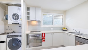 A modern kitchen with a washing machine, oven, and a fire extinguisher sign.