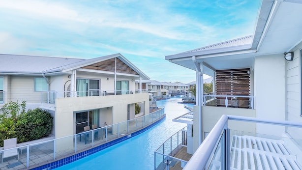 A modern hotel with a pool, multiple balconies, and a clear view of the pool area.