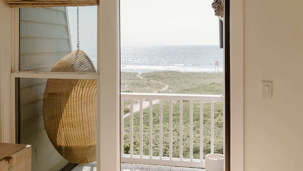 Une chambre dotée d’une grande fenêtre donnant sur un balcon avec vue sur l’océan.