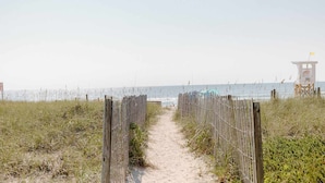 Un sentier de sable qui longe la plage et mène à un poste de surveillance des sauveteurs.