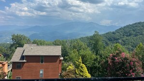 A residential area with a two-story house, surrounded by lush greenery and mountains in the background.