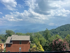 A residential area with a two-story house, surrounded by lush greenery and mountains in the background.