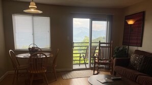 A living room with a dining table, chairs, a sofa, a coffee table, and a view of mountains through a sliding door. - Free Ticket to Dollywood, Anakeesta, and Other Area Attractions! (Gatlinburg)