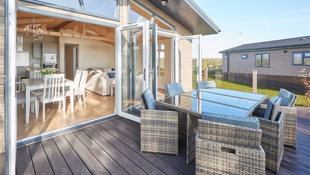 A modern house with a glass-enclosed patio, a dining area with white furniture, and a kitchen visible through the glass doors. - Host Stay Salt Seaweed (Saltburn-by-the-Sea)