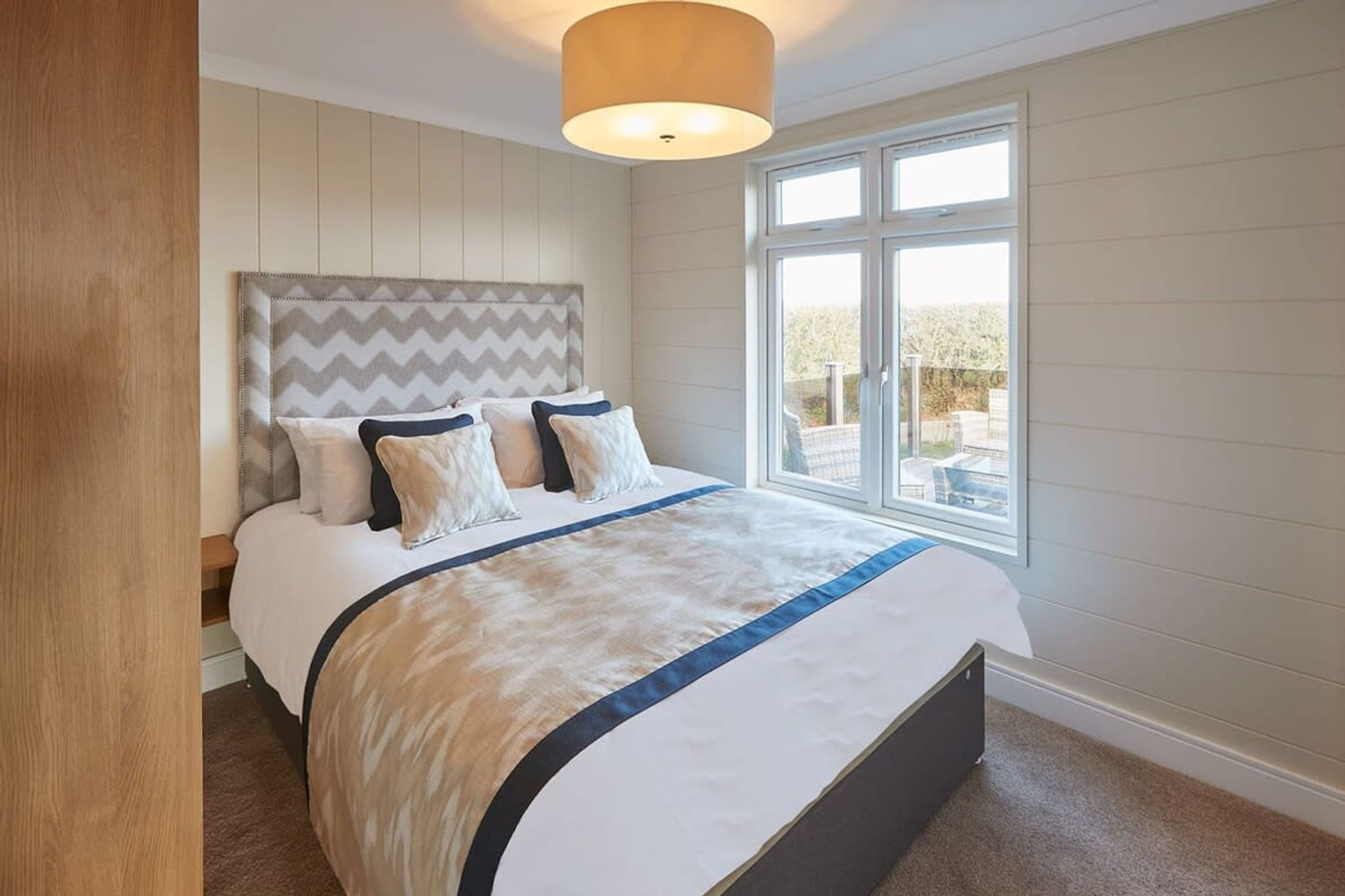 Une chambre à coucher avec un lit, une fenêtre et un luminaire au plafond.