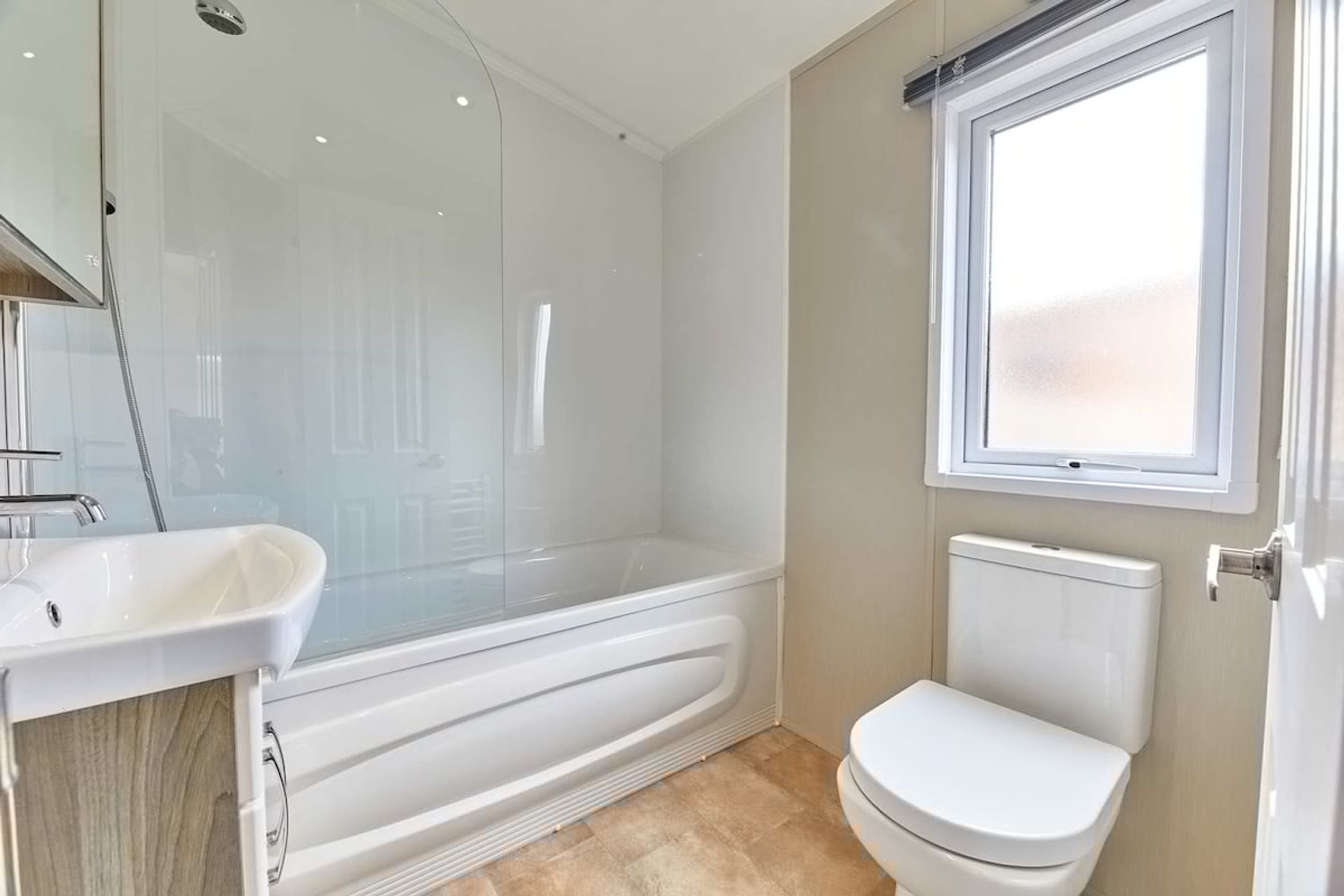 A bathroom with a glass-enclosed shower, a white sink, and a toilet.