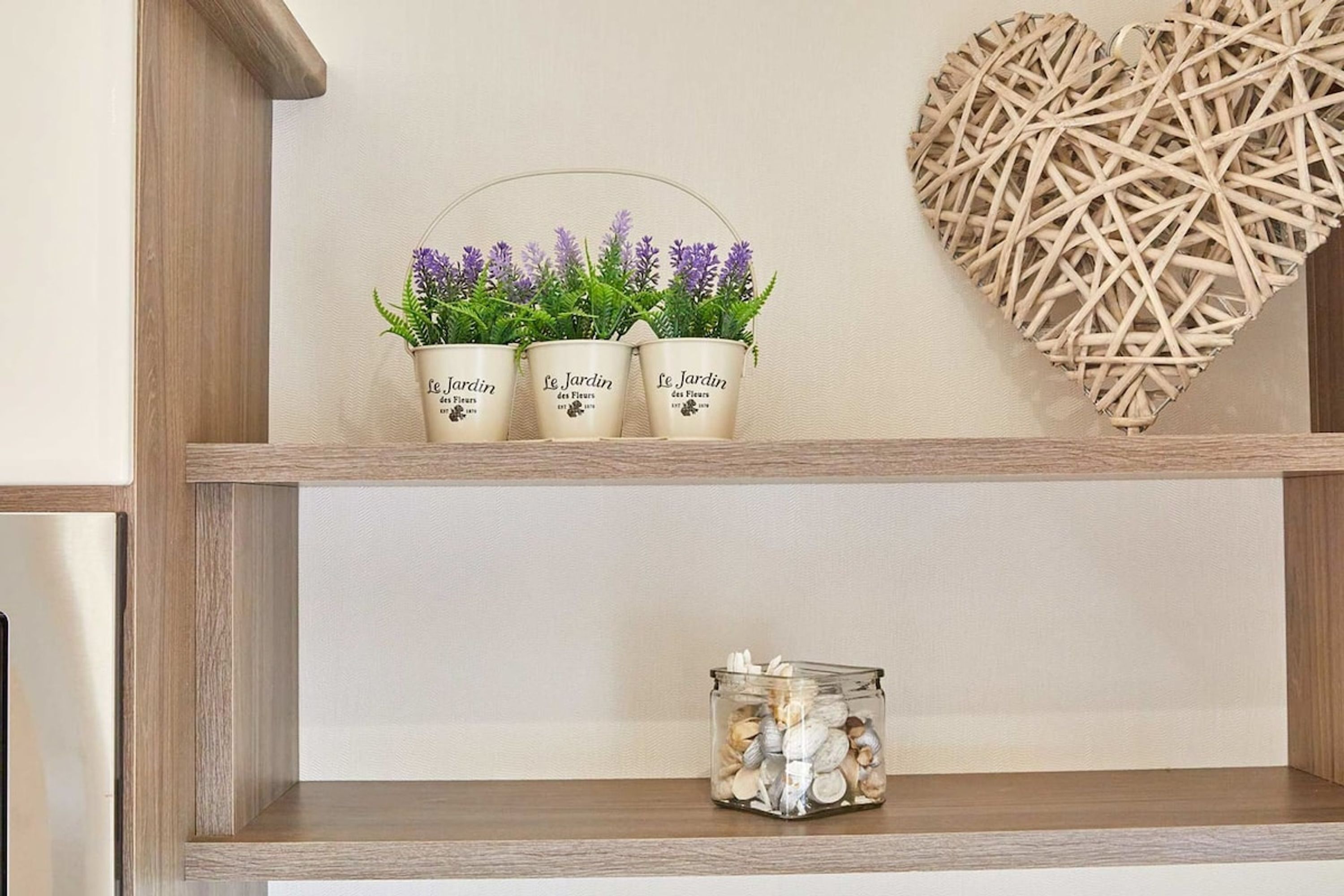A shelf with three potted plants and a glass jar.