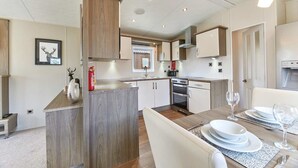 Una cucina moderna con mobili in legno, un'isola centrale e un'area da pranzo con un tavolo apparecchiato per due.