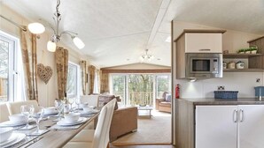 A dining area with a long table set for a meal, a kitchen with modern appliances, and a view of the outdoors. - Host Stay Yolo Lodge (Morpeth)