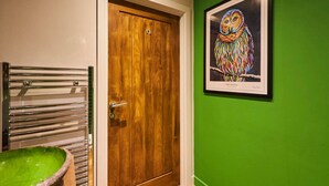 A bathroom with a wooden door, a green wall, and a framed owl painting. - Host Stay Forest Green Lodge (Alnwick)