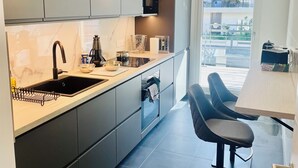 A modern kitchen with a built-in oven, a sink, and a dining area with two chairs.