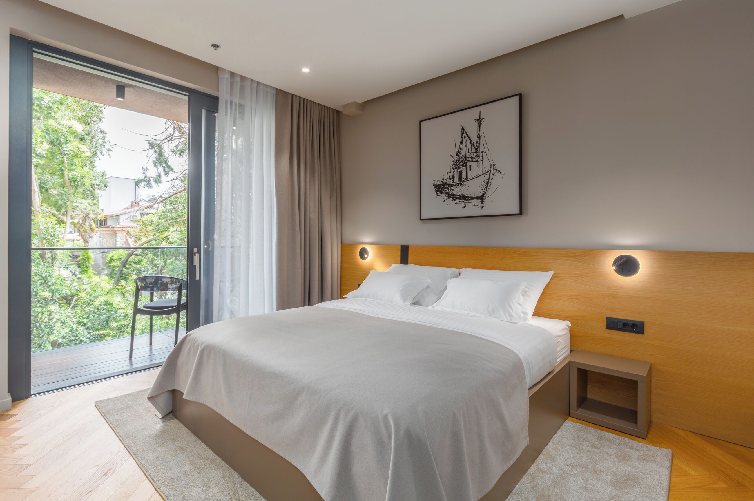 A modern bedroom with a large bed, a wooden headboard, a nightstand, and a balcony with a chair.