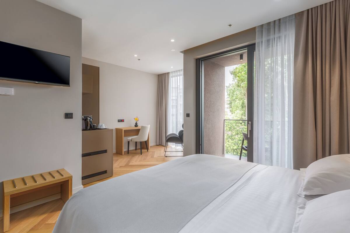 A modern hotel room with a large bed, a desk, and a TV.