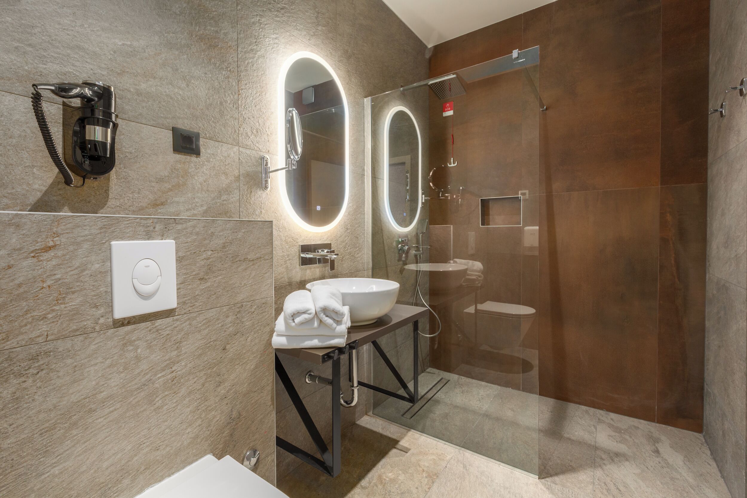A modern bathroom with a large mirror, a sink, and a shower.