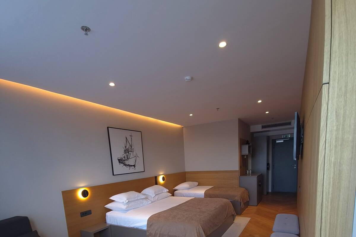 A modern hotel room with a bed, sofa, small table, and a TV.