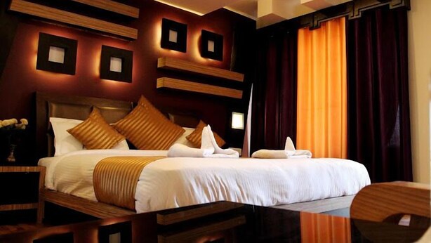 A hotel room with a large bed, dark curtains, and modern wall decor. - Hotel Ladakh Marvel Leh (Leh)