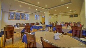 A large dining hall with multiple tables and chairs, high ceilings with recessed lighting, and large windows allowing natural light. - Hotel Ladakh Marvel Leh (Leh)