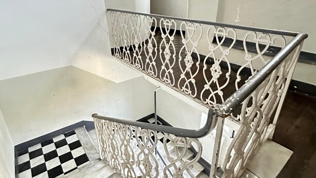 A staircase with a metal railing and a checkered floor pattern. - ANCIENT GENOESE ATTIC (Genova)