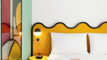 A hotel room with a bed, a bedside table with a lamp, and a wall with a wavy design.