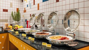 Un buffet con diverse opzioni alimentari, una pianta e una parete decorativa con motivo geometrico.