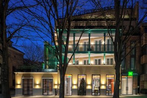 Ein mehrstöckiges Gebäude mit einem grünen Balkon und einem gut sichtbaren Eingang, mit einem Schild für das Hotel 'Ibis'.