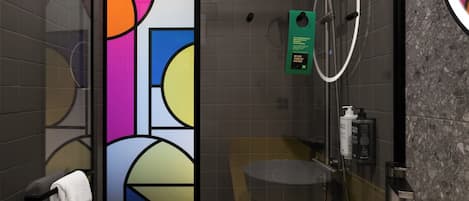 Un baño moderno con separador de vidrio, toallero, lavamanos y espejo.
