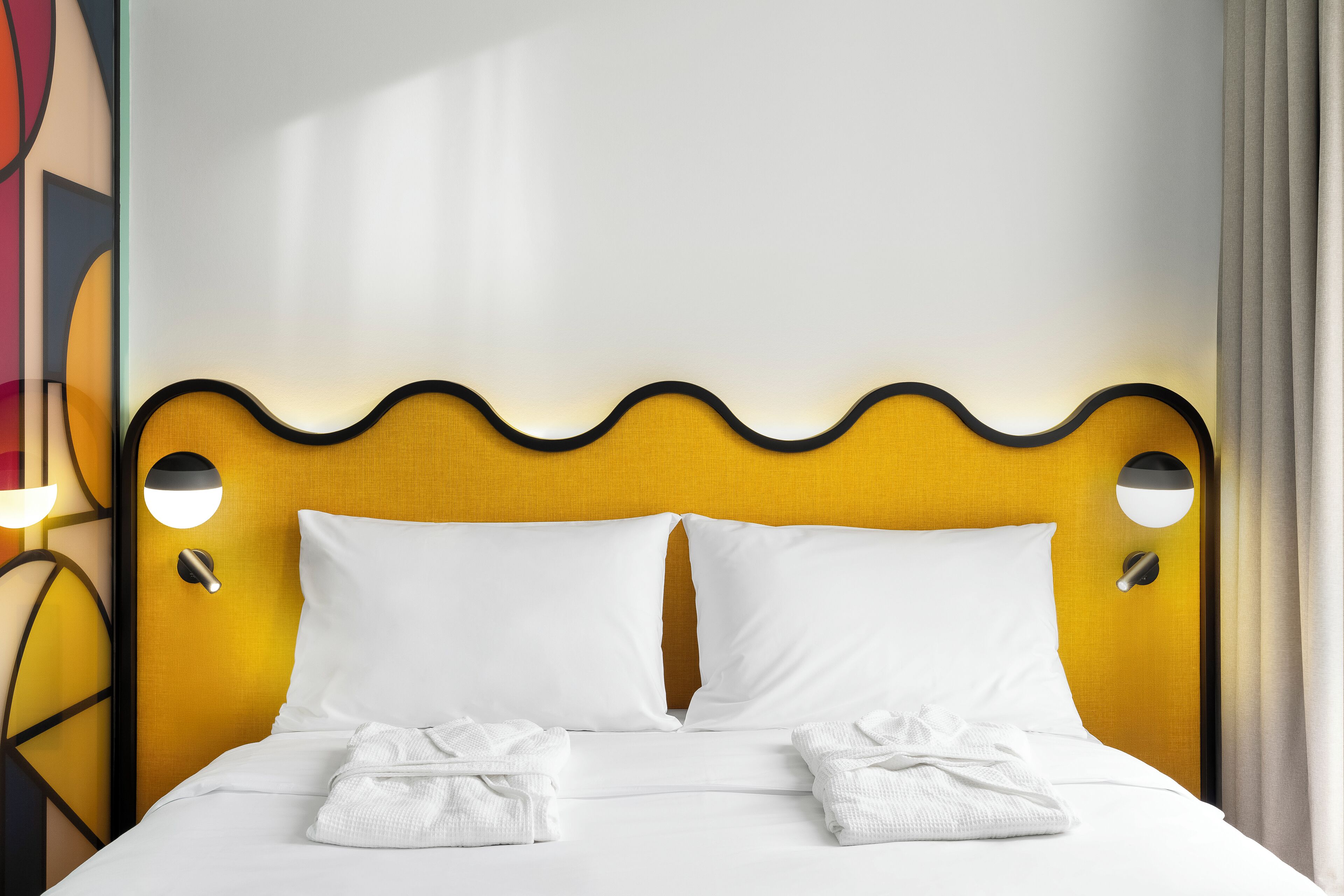 A bed with white linens, two pillows, and two folded towels.