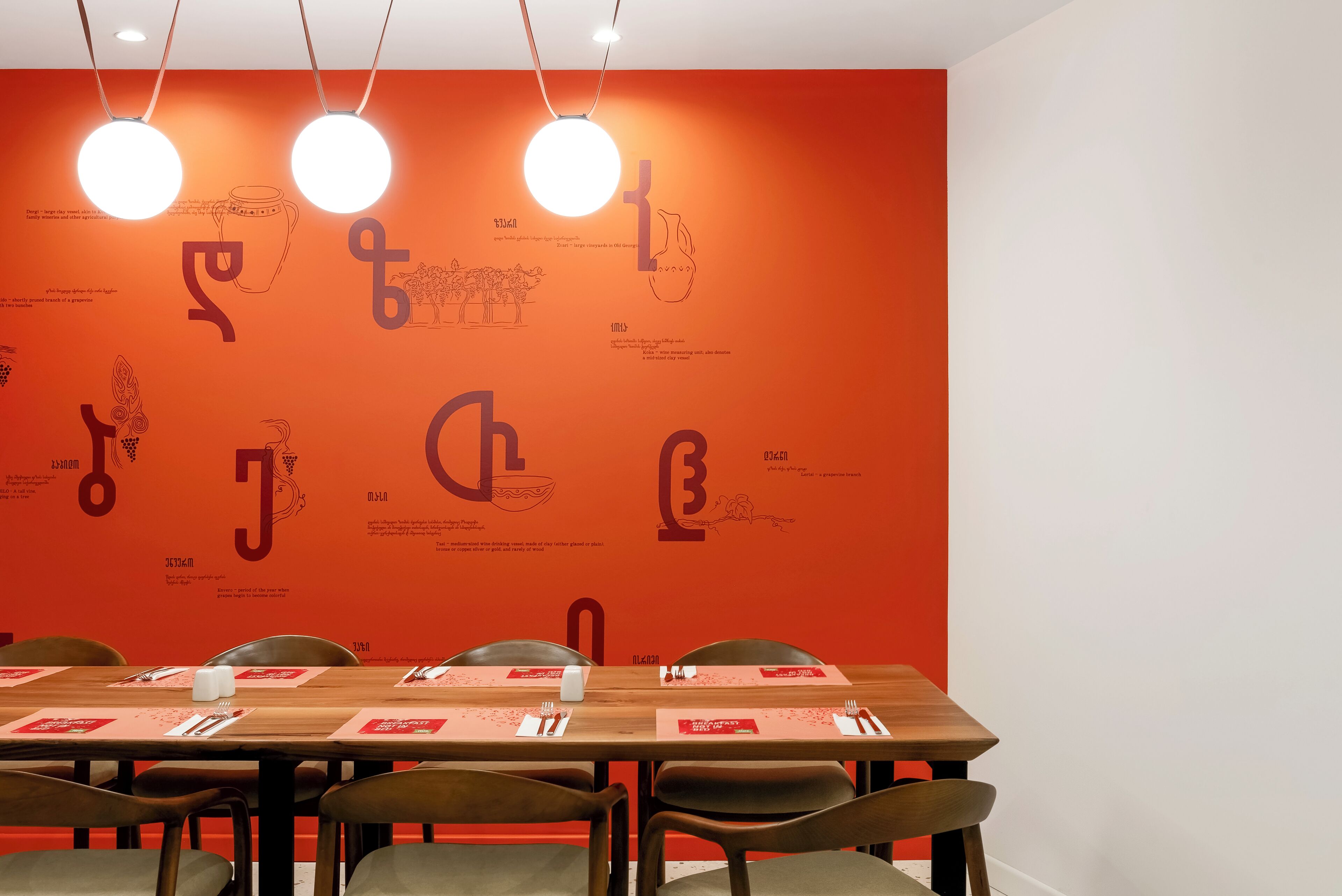 A conference room with a long table, chairs, and a red wall with text and illustrations.
