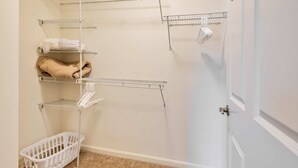 A laundry room with metal shelves, a white basket, and a beige towel. - Gorgeous Apt with Kitchen (Lexington)