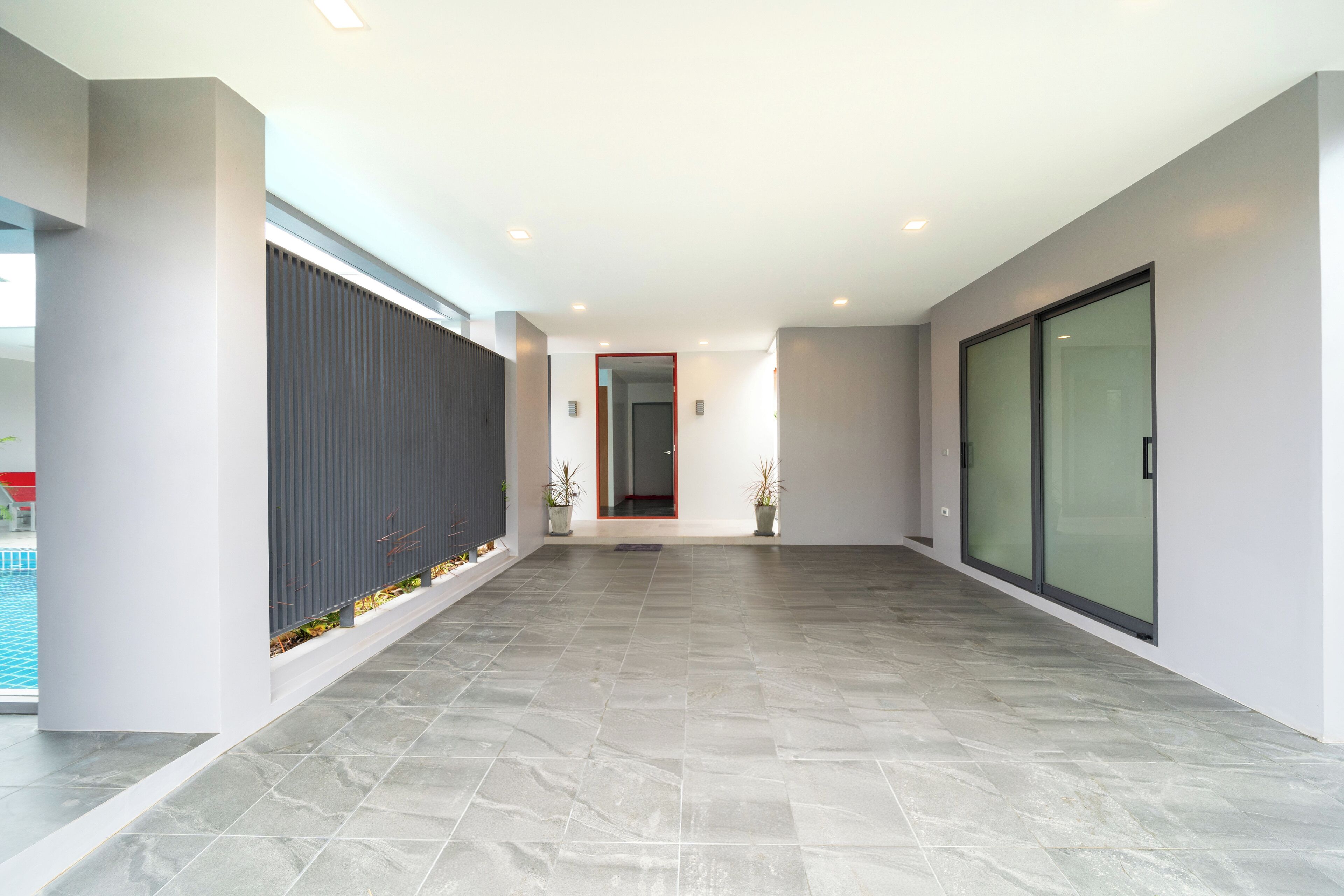 A spacious hallway with a tiled floor, a modern entrance, and a glass door on the right.
