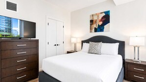 Ein modernes Hotelzimmer mit einem großen Bett, einem Schminktisch, einem Fernseher und einem Bild an der Wand.