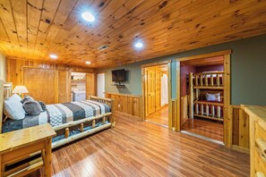 A wooden-floored room with a bed, a TV, and a storage area with shelves. - A Million Dollar View | By Colonial Properties (Gatlinburg)