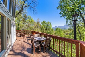 A wooden deck with outdoor furniture, a view of a mountainous landscape, and a street lamp. - A Million Dollar View | By Colonial Properties (Gatlinburg)