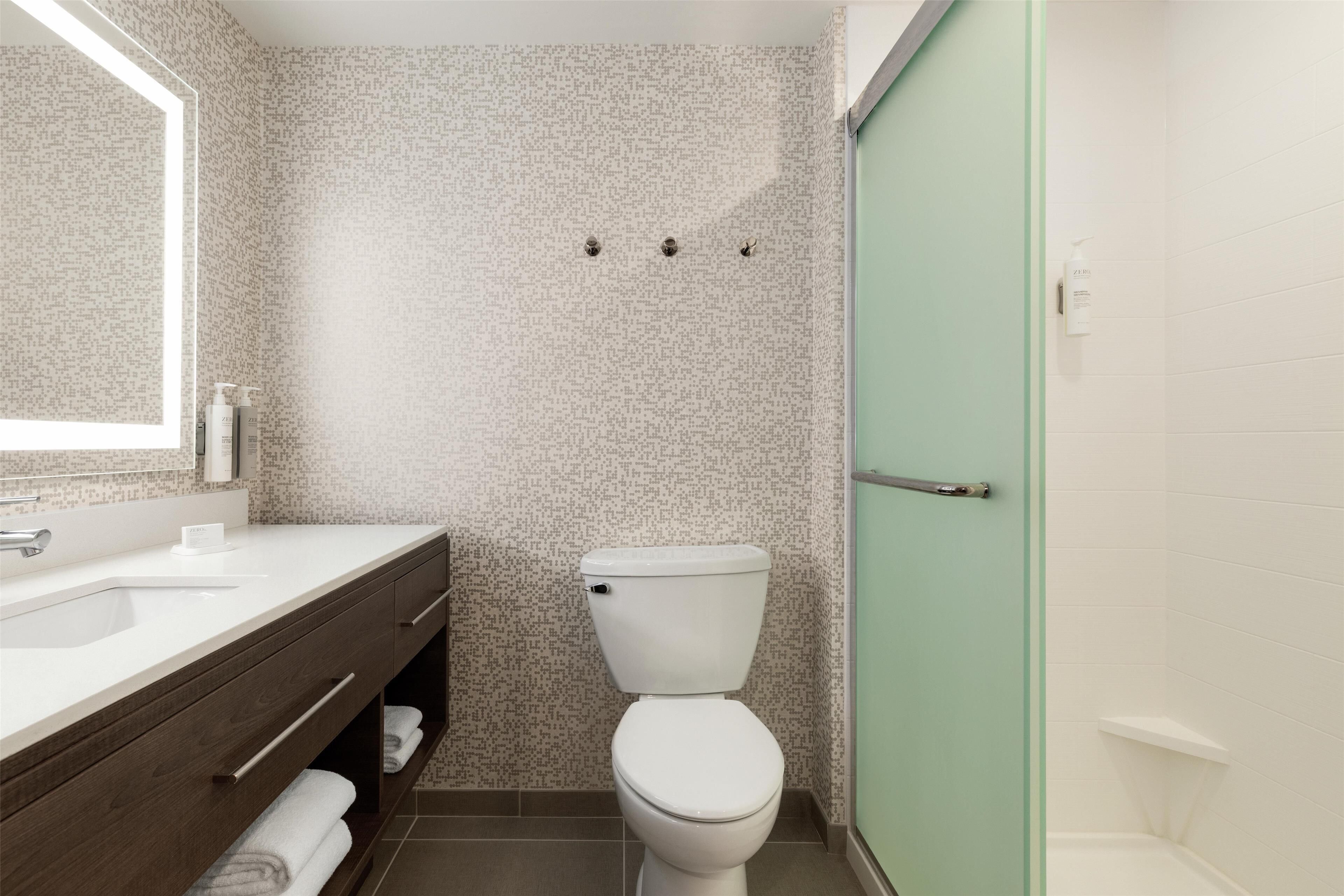 A bathroom with a white toilet, a sink with a mirror, and a shower area.