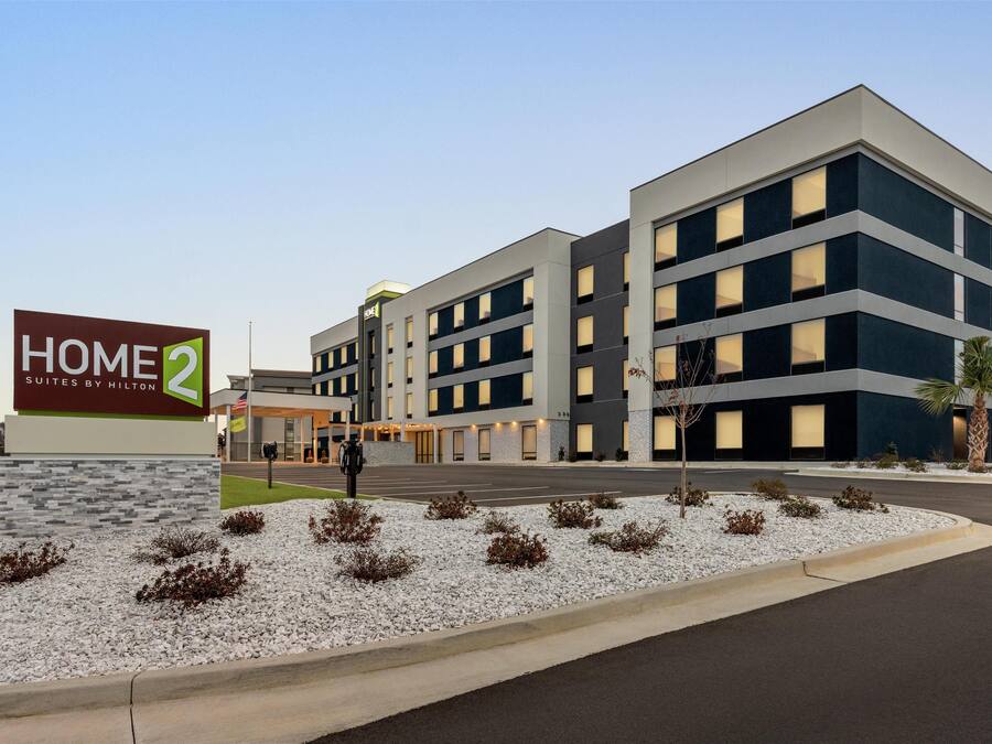 A modern hotel with a sign reading "HOME 2 Suites by Hilton".