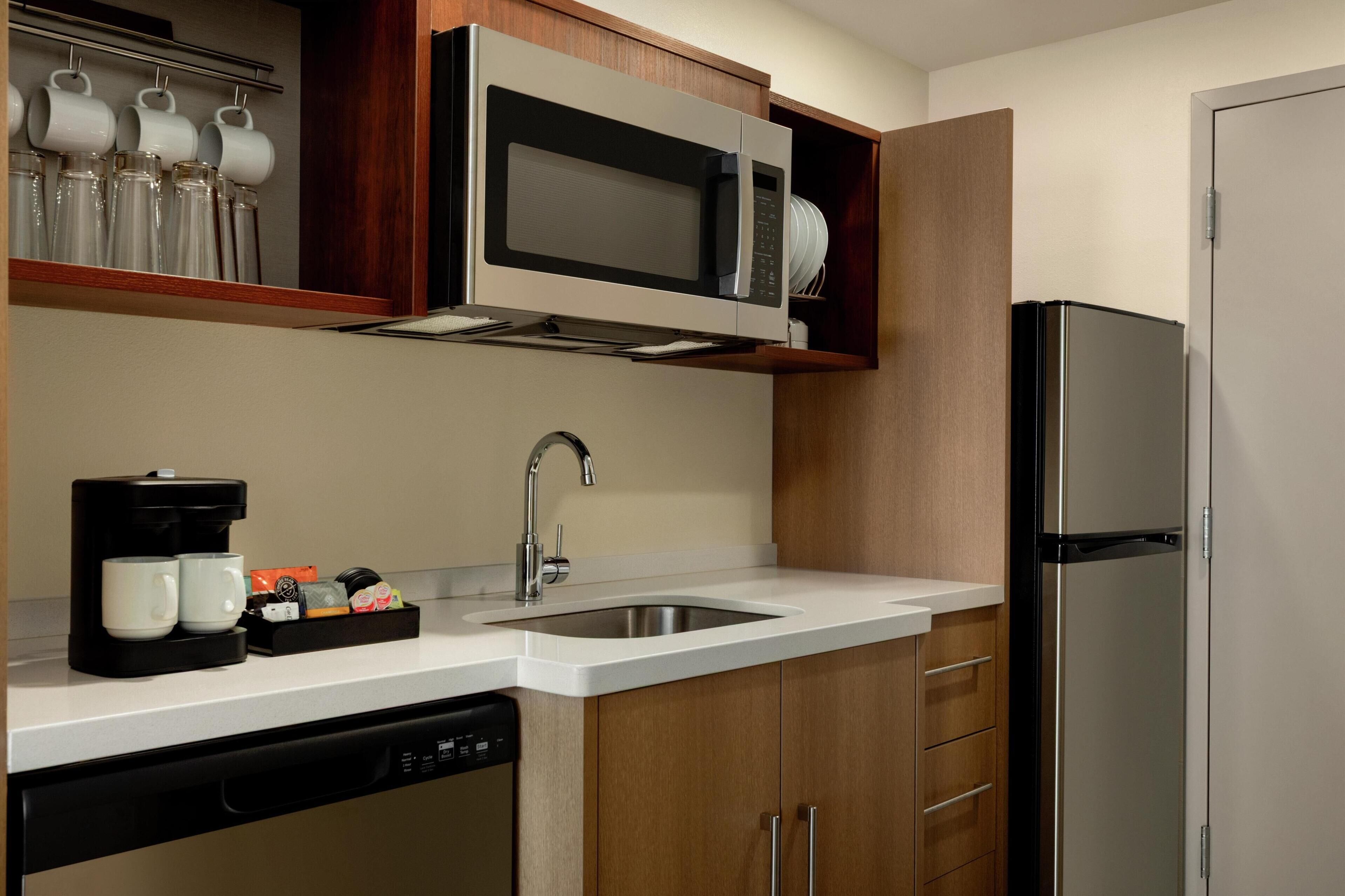 A kitchen with a stainless steel refrigerator, a microwave, a sink, and a coffee maker.