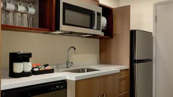 A kitchen with a stainless steel refrigerator, a microwave, a sink, and a coffee maker.